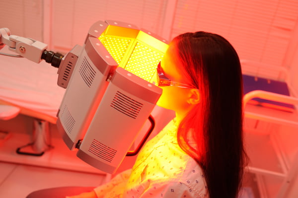 red light therapy. The girl goes through a course of skin rejuvenation with the help of red light treatment.
